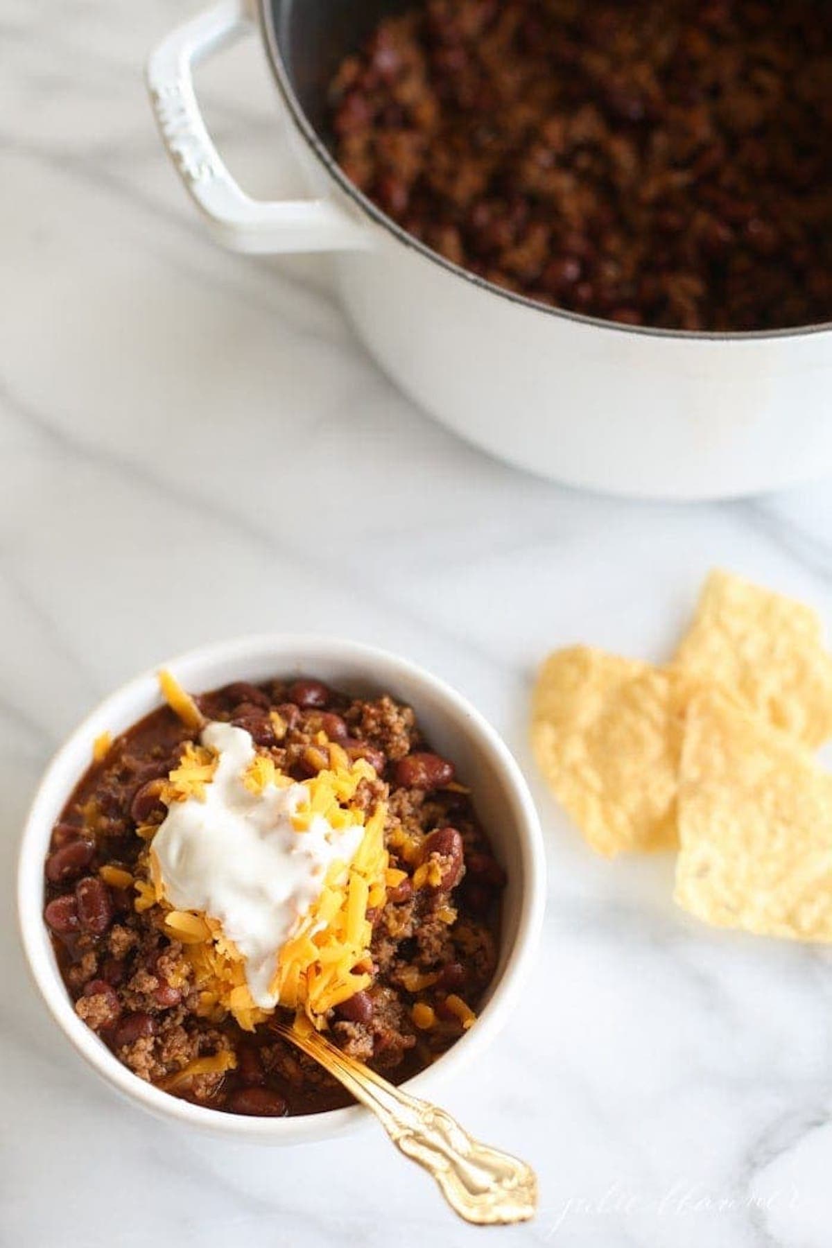 An easy and quick chili recipe garnished with sour cream and tortilla chips.