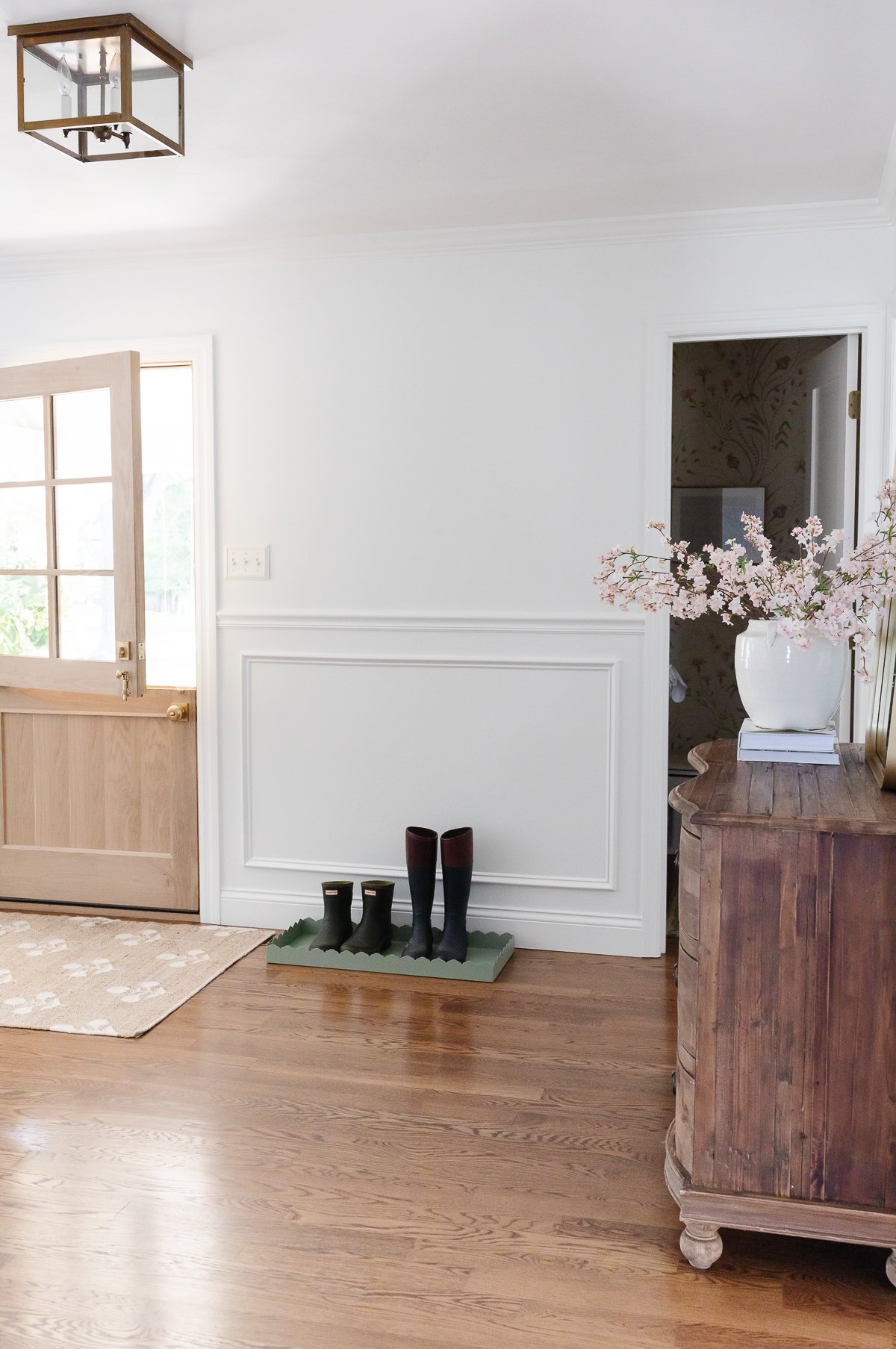 A living room with hardwood floors and a door featuring a curved dresser.