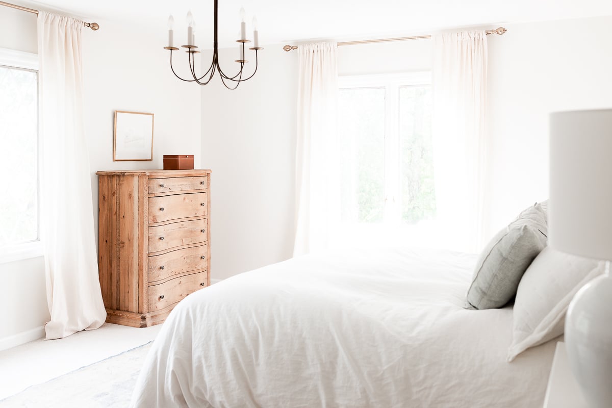 A white bedroom with a curved dresser.