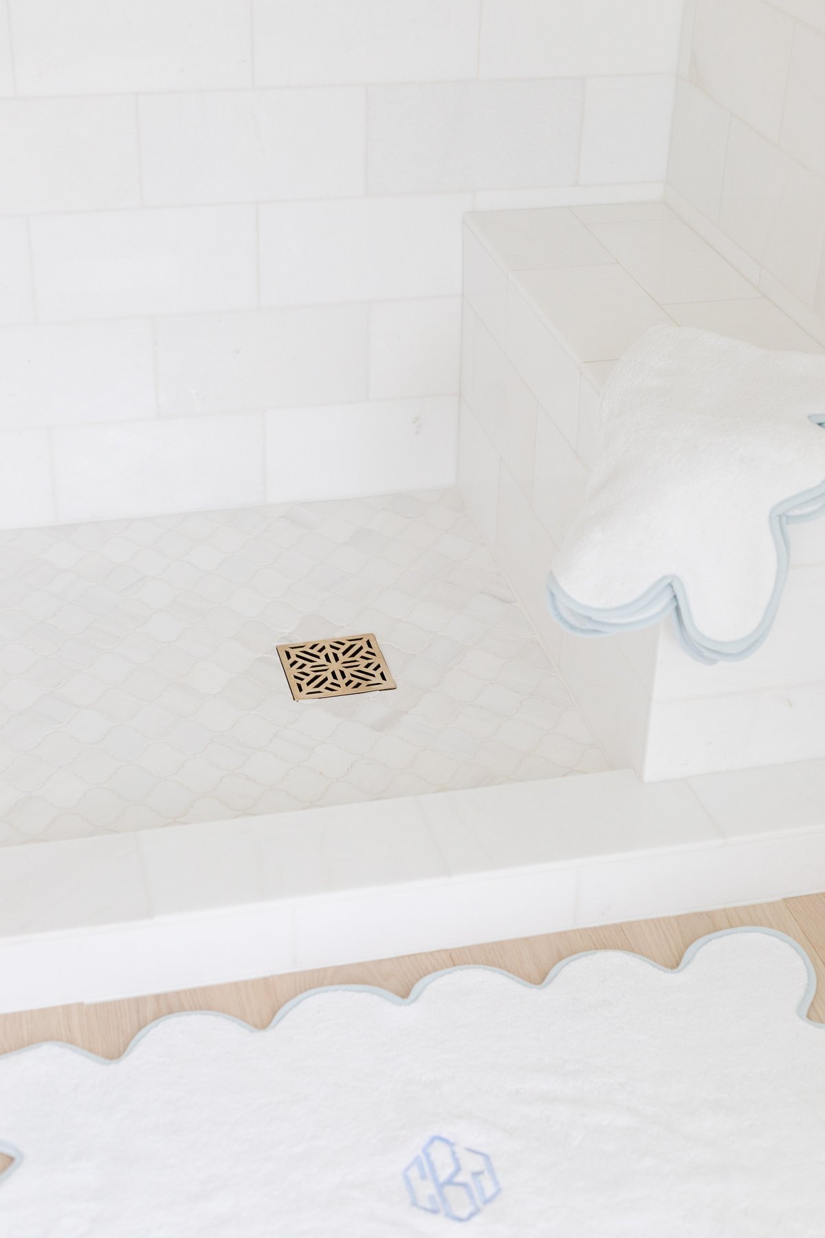 A bathroom with a white shower stall and a blue shower rug.