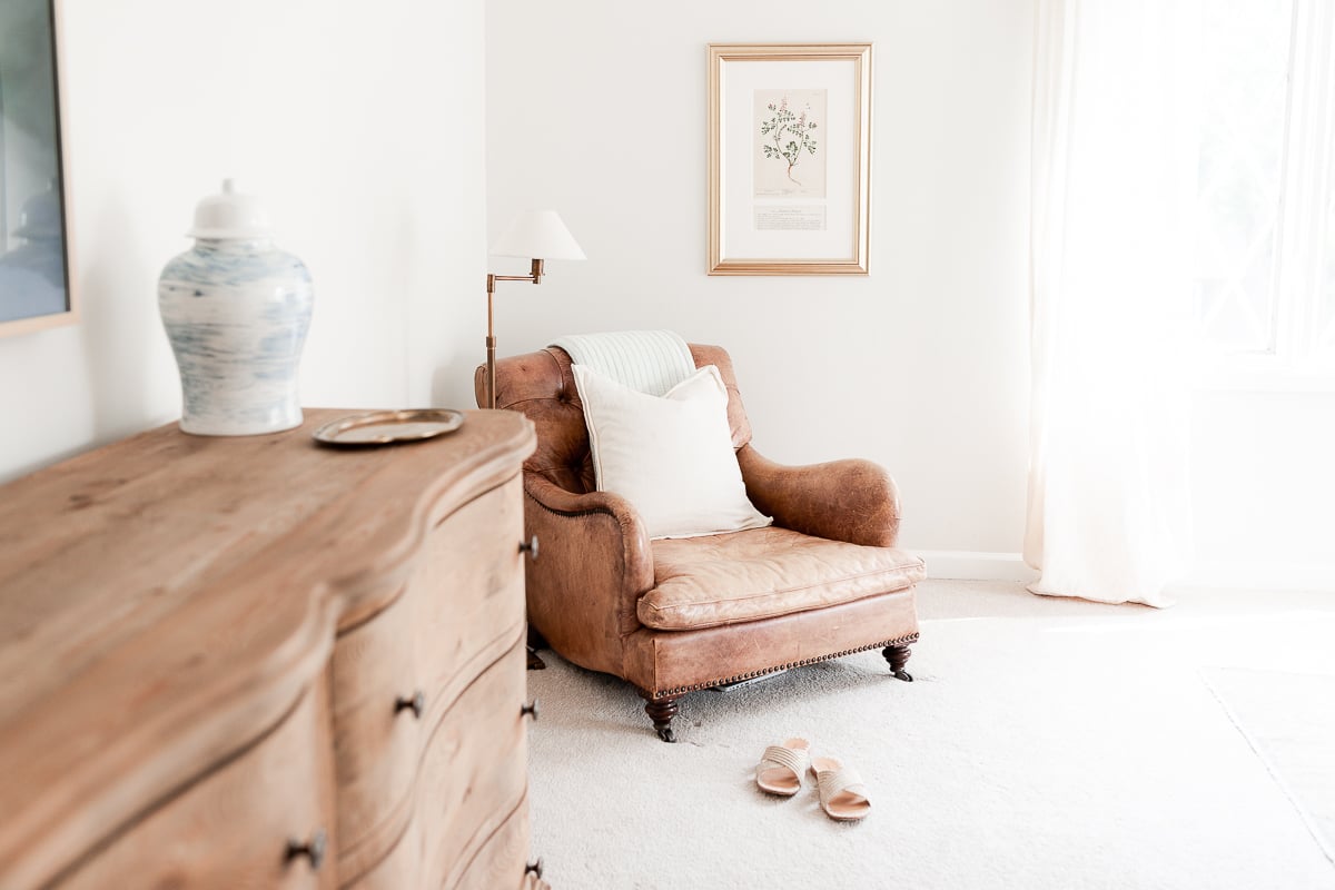 A curved chair in a room with a painting on the wall.