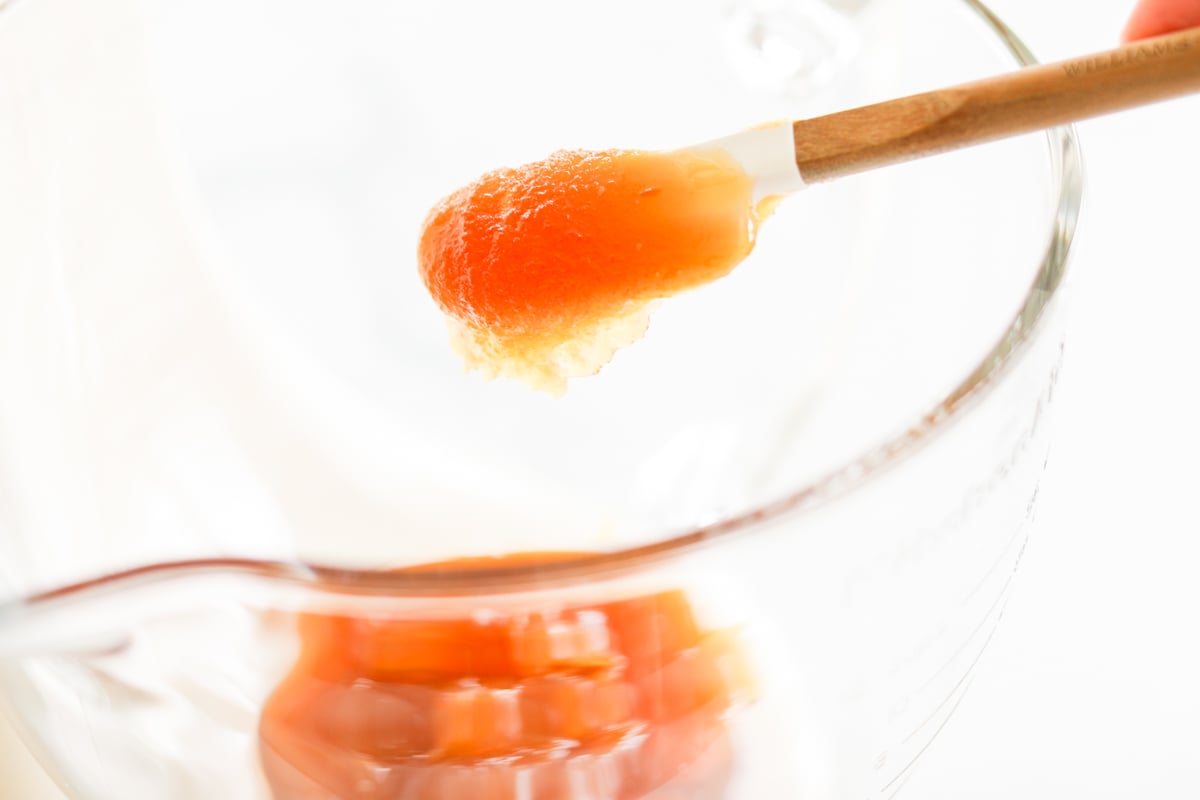 A person is pouring orange juice into a blender.