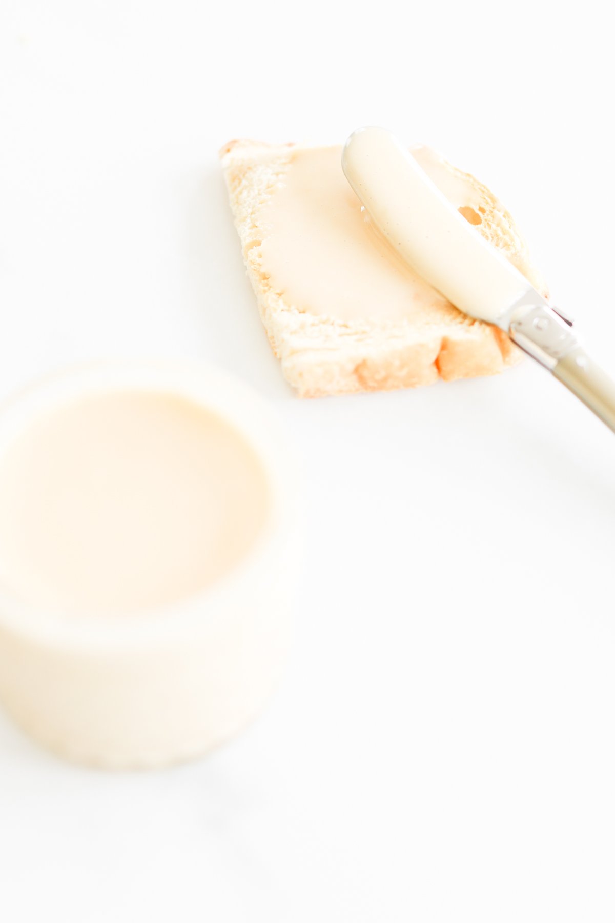 A small jar of whipped honey and a piece of bread.