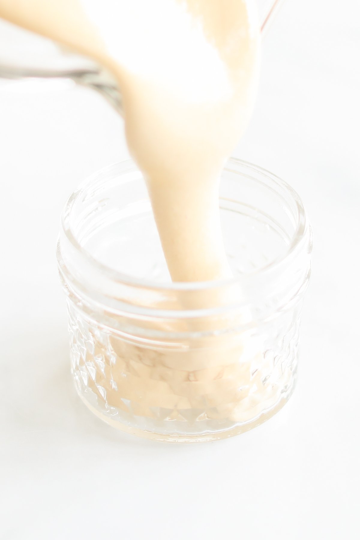 A jar of whipped honey on a white surface.