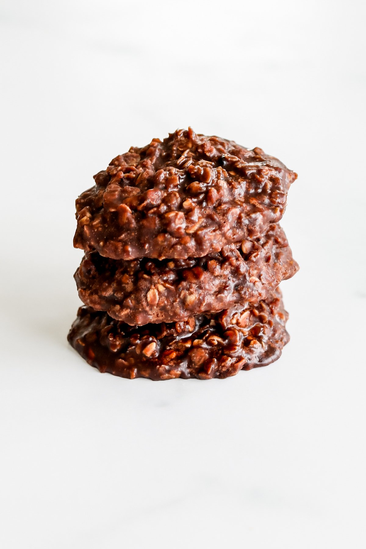 A stack of chocolate no bake cookies, also known as preacher cookies, on a white surface.