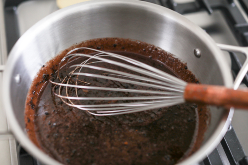 A pot with a whisk in it on top of a stove, cooking preacher cookies.