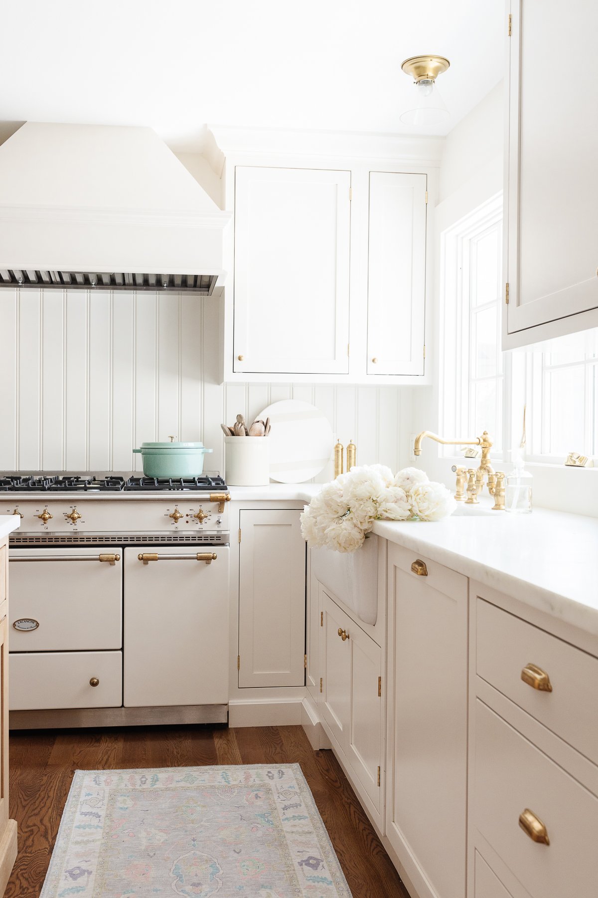 A white kitchen with a rug on the floor, before.