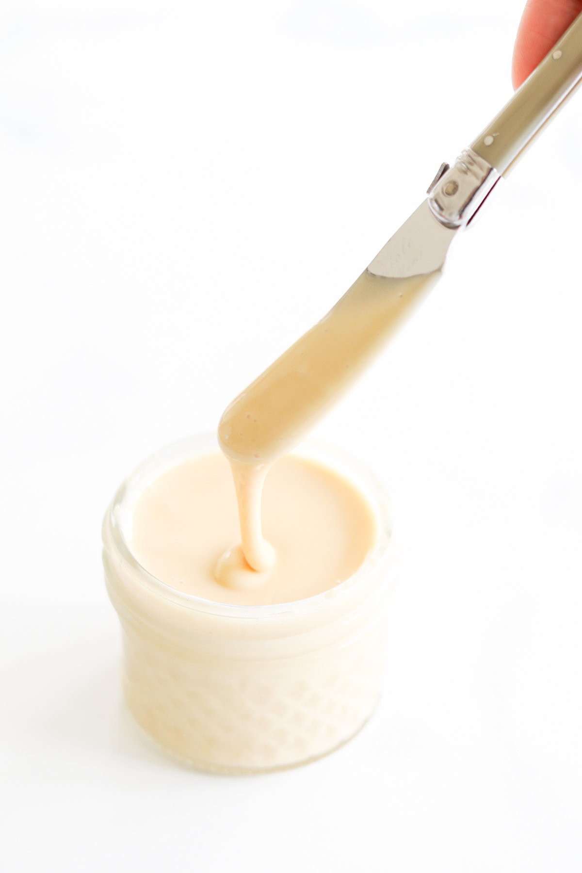 A knife in a small jar of whipped honey.