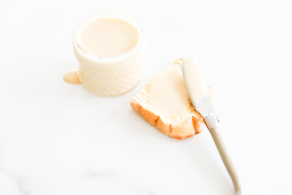 A slice of bread next to a glass of milk.