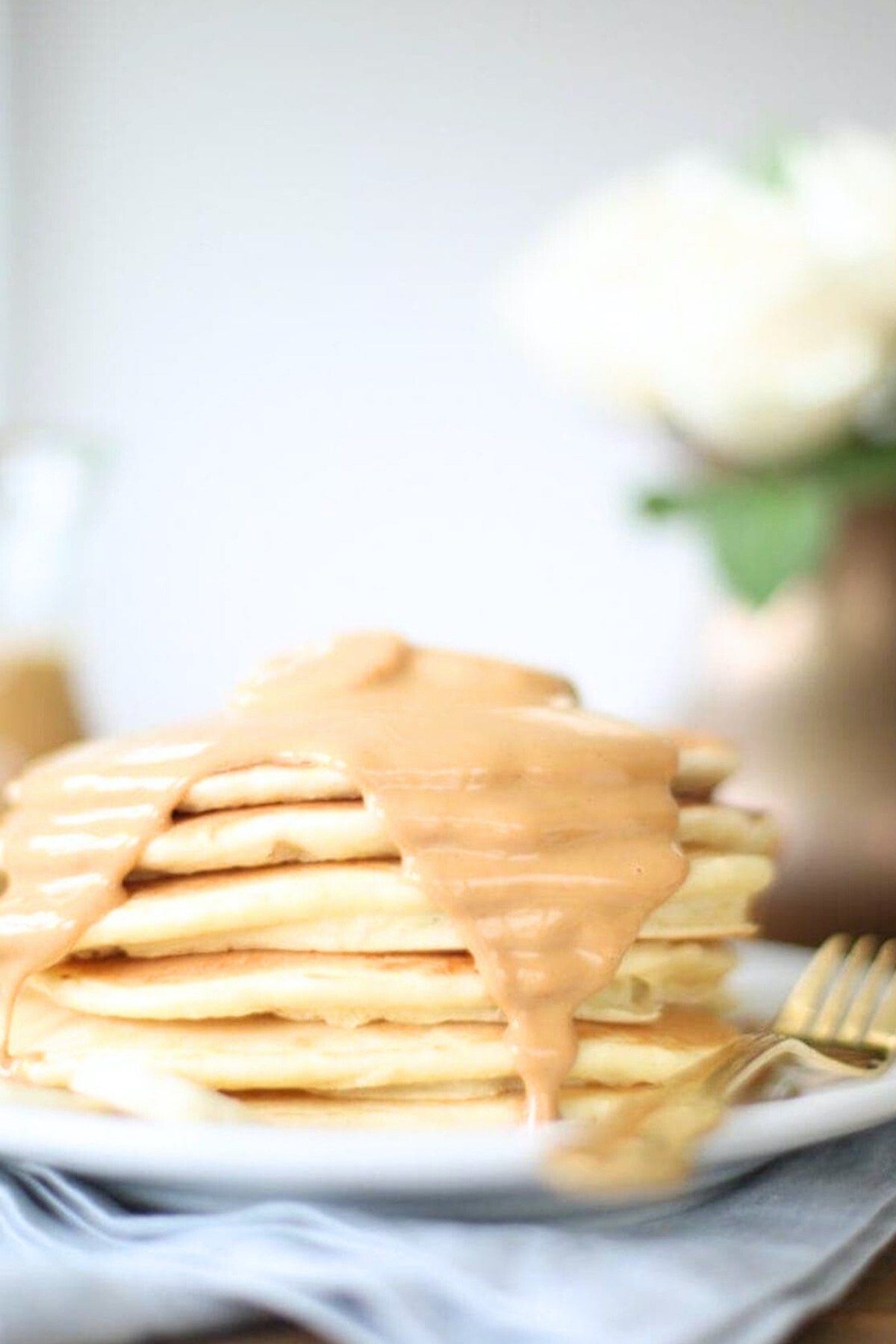 A classic stack of pancakes drizzled with caramel sauce on a plate.