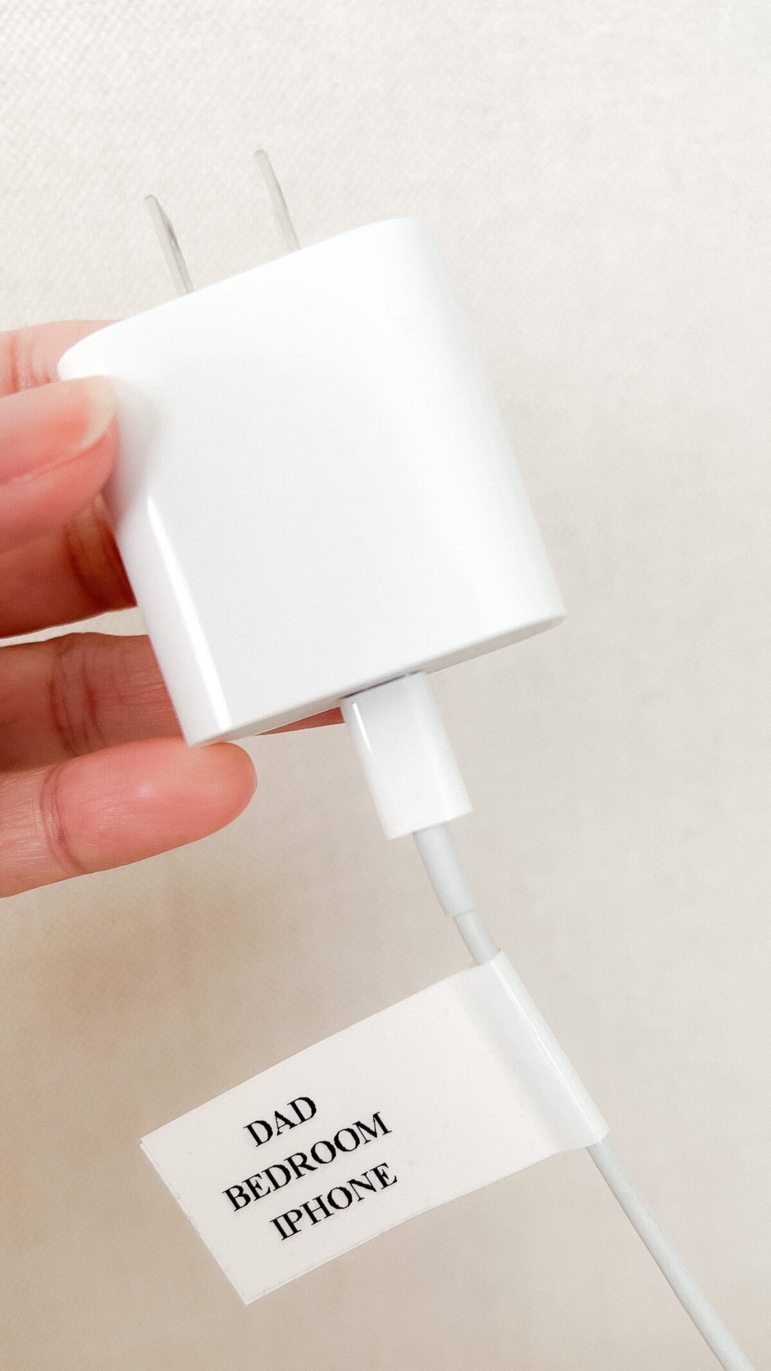 A person holding an Amazon charger with a note attached to it.