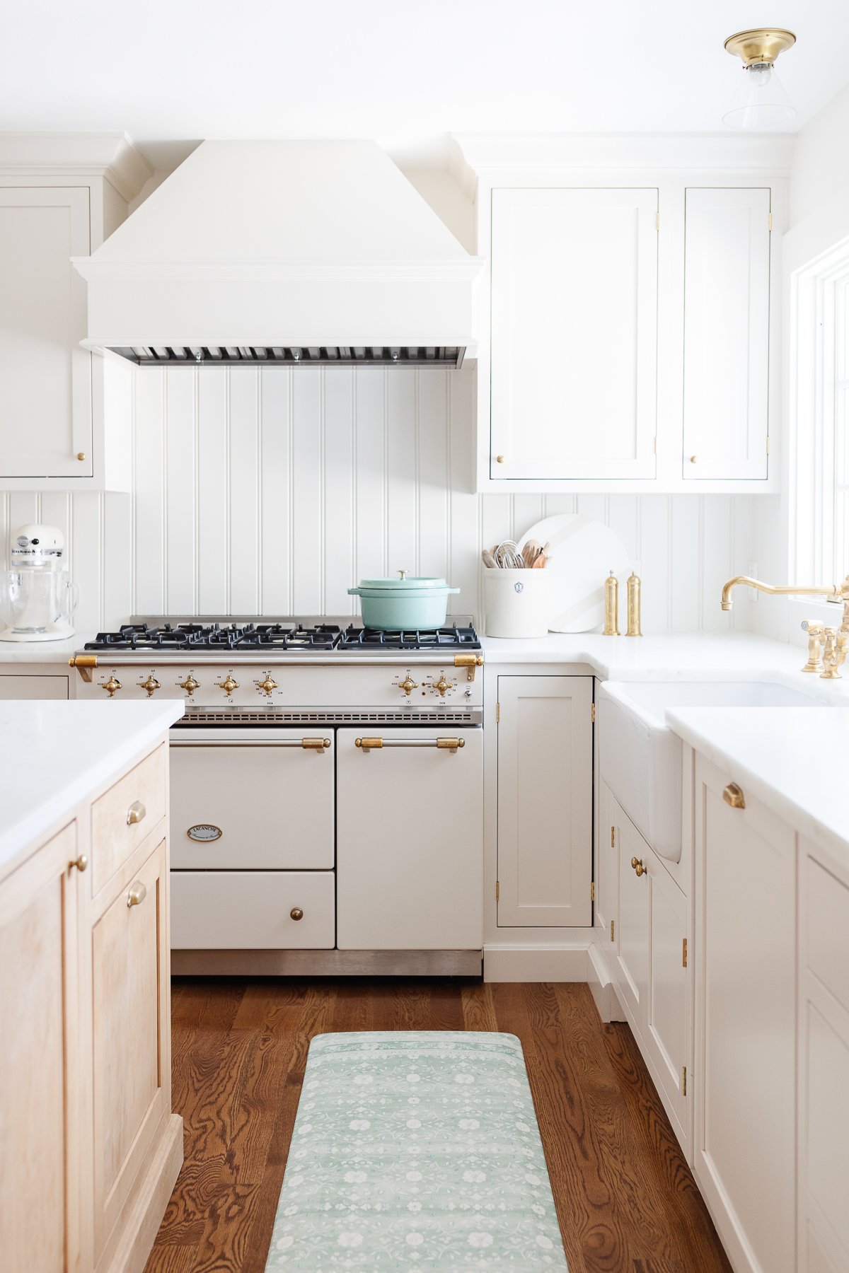 A classic kitchen with white cabinets and a green rug.