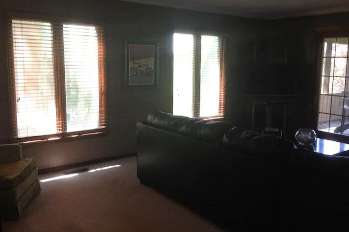 A living room with large windows and blinds ideal for music room ideas.