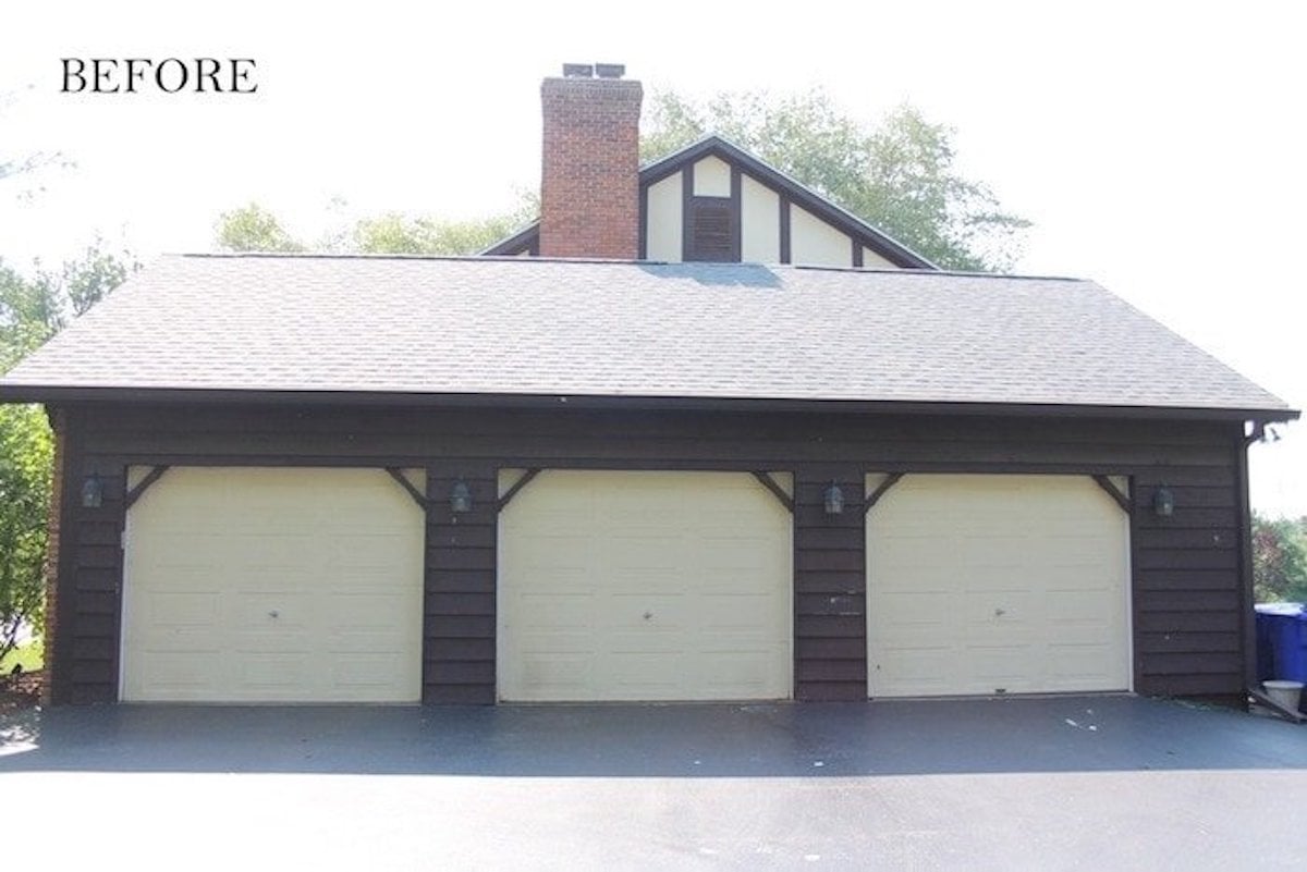 A house with two garages and a driveway, featuring copper lanterns lining the outdoor walls.