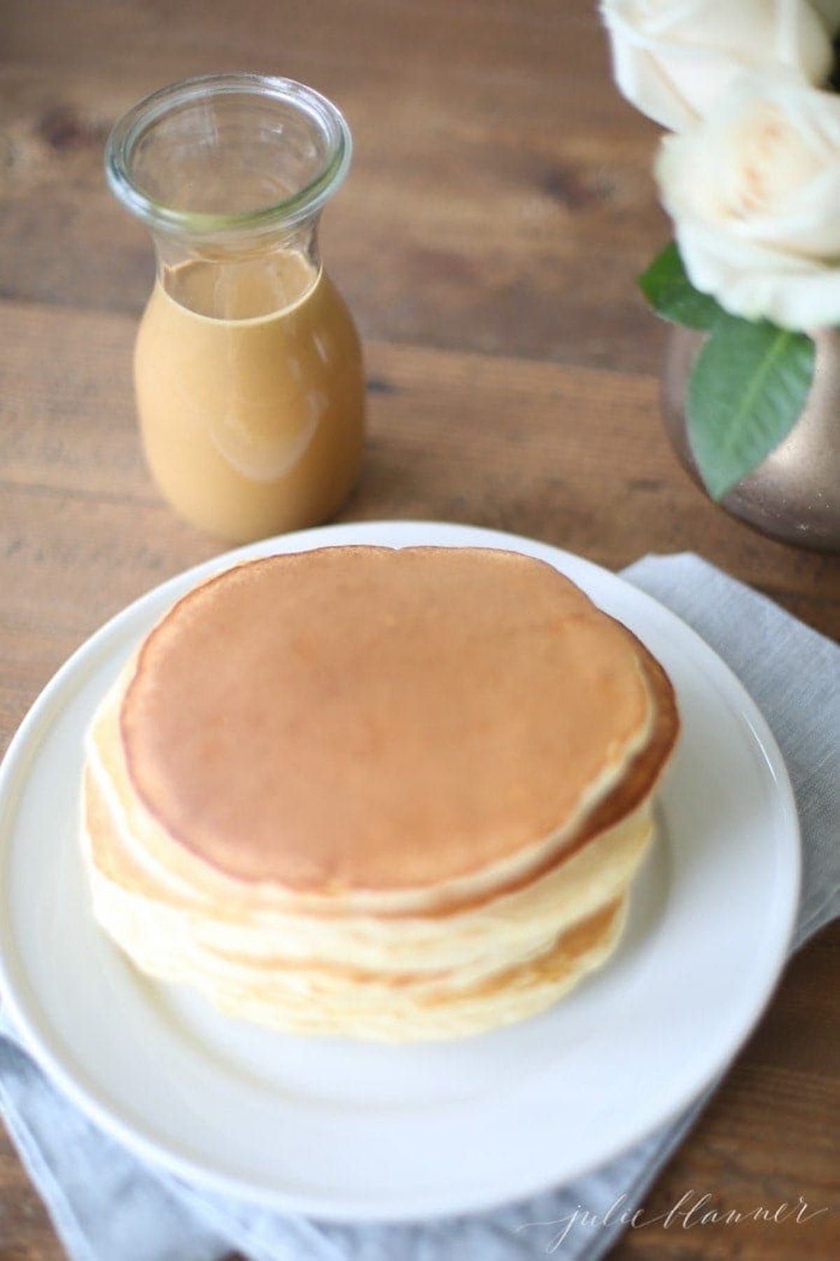 Classic pancakes on a plate next to a glass of milk.