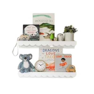A white shelf with books, toys and a koala.