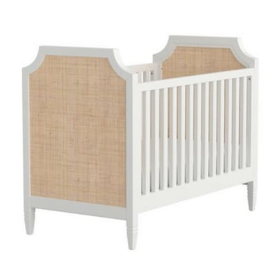A white crib with a rattan headboard.