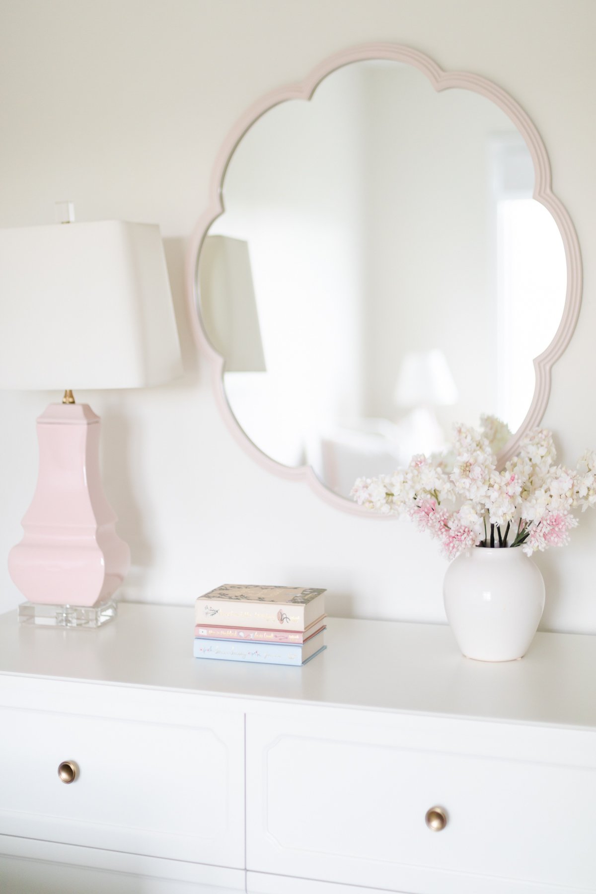 A white dresser with pink flowers and a mirror.