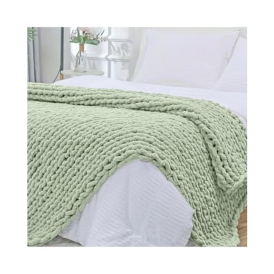 A green knitted blanket on a bed with a Pottery Barn Kids vibe.