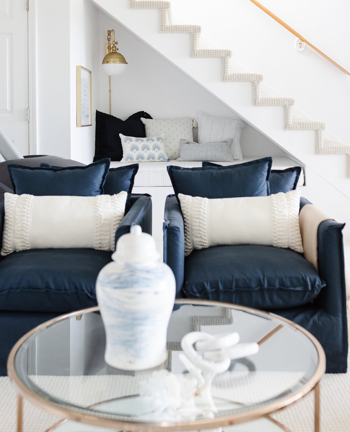 A living room with two blue chairs and a glass coffee table.