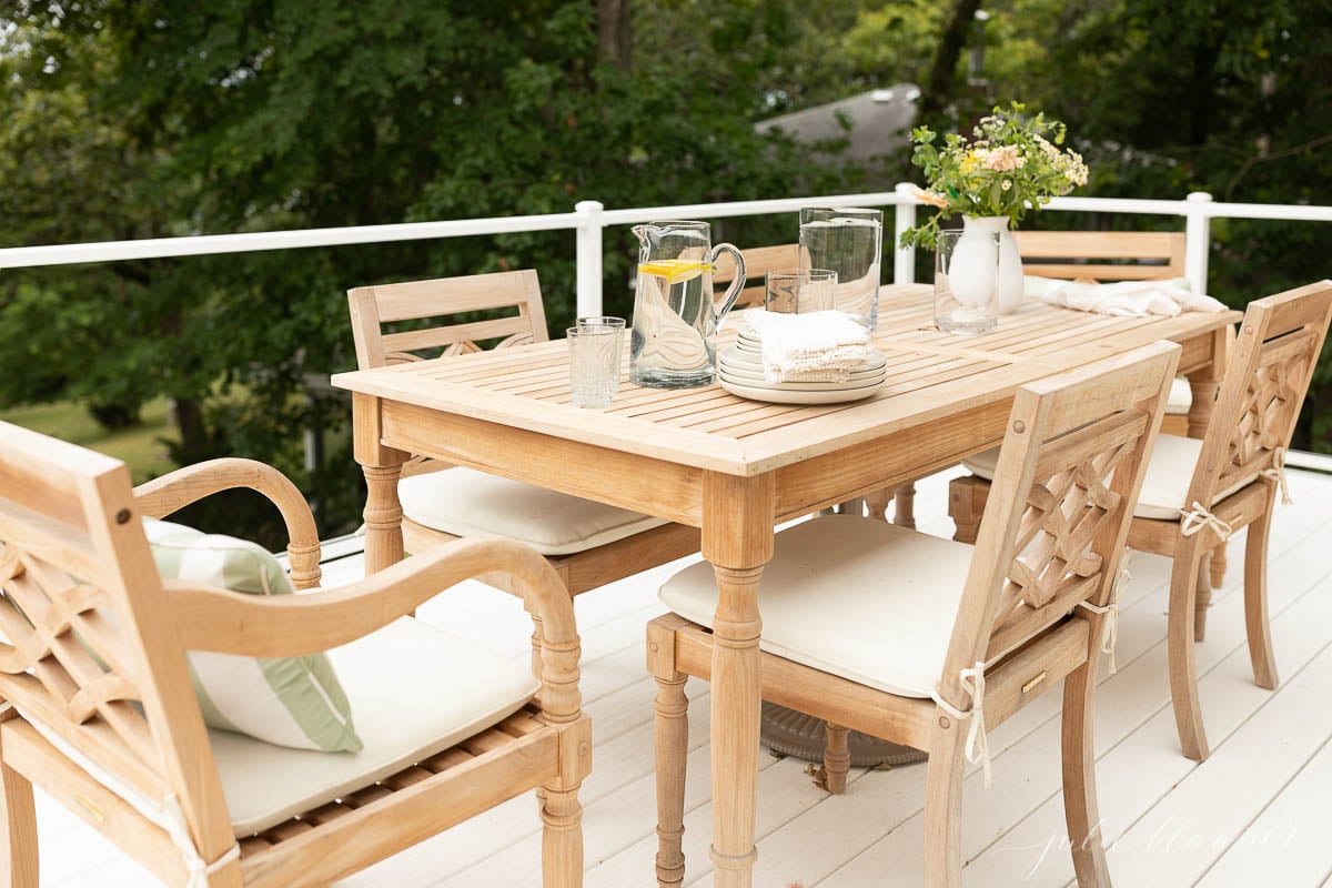 A set of patio furniture comprising a wooden dining table and chairs on a deck.