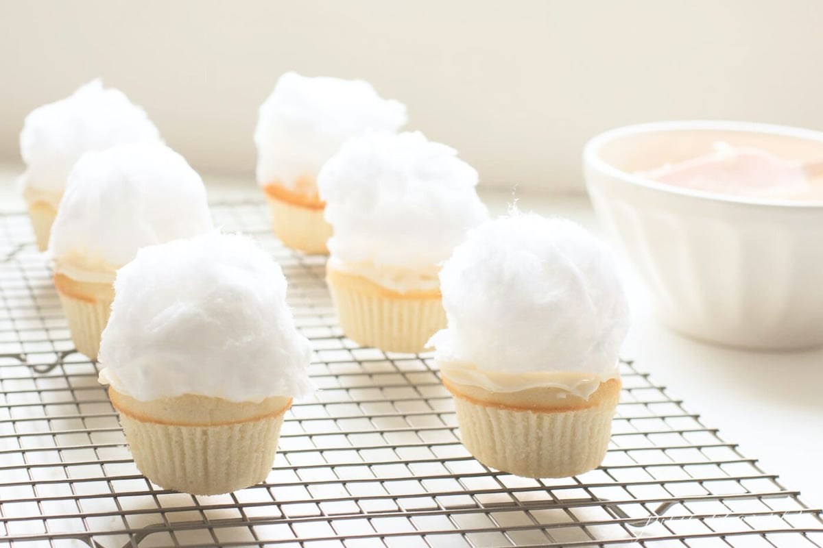 Cotton candy bunny tail cupcakes on a cooling rack. 