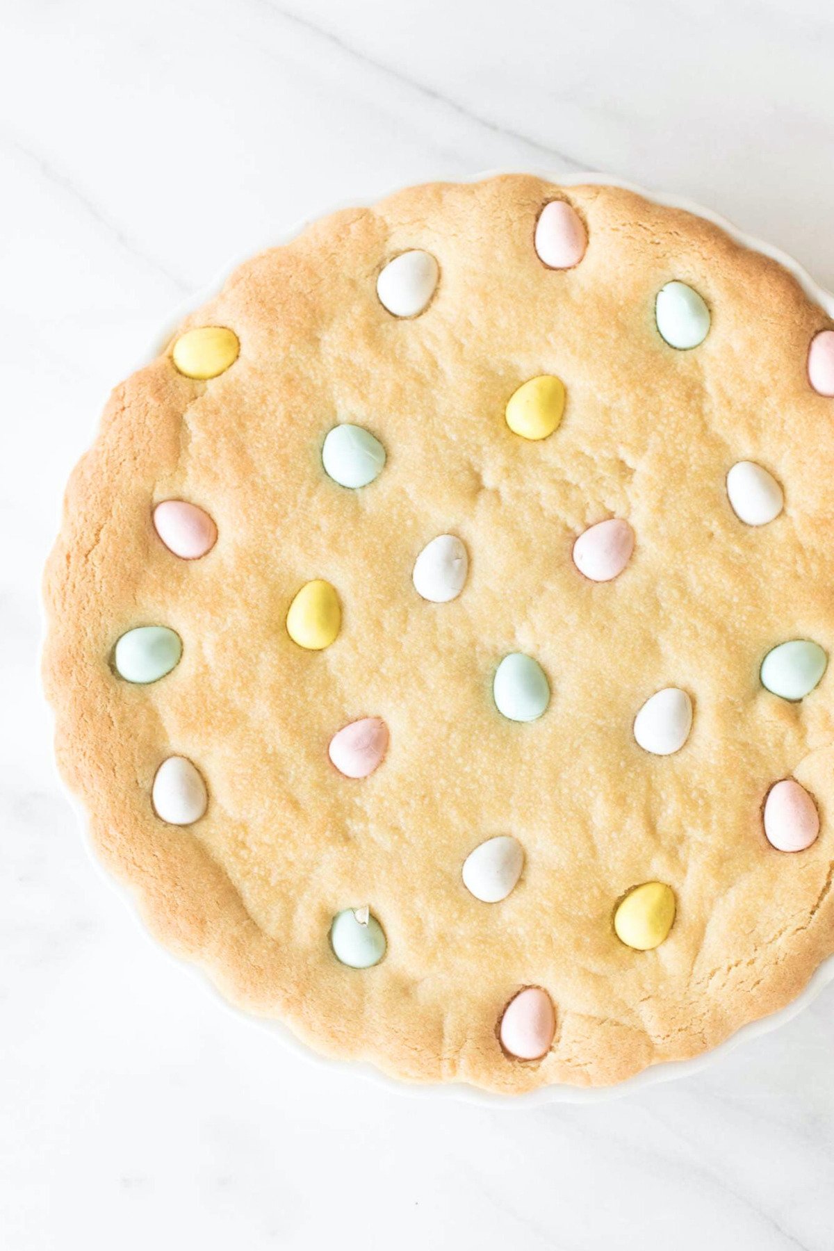 An Easter cookie cake with Cadbury eggs, baked in a white tart pan.