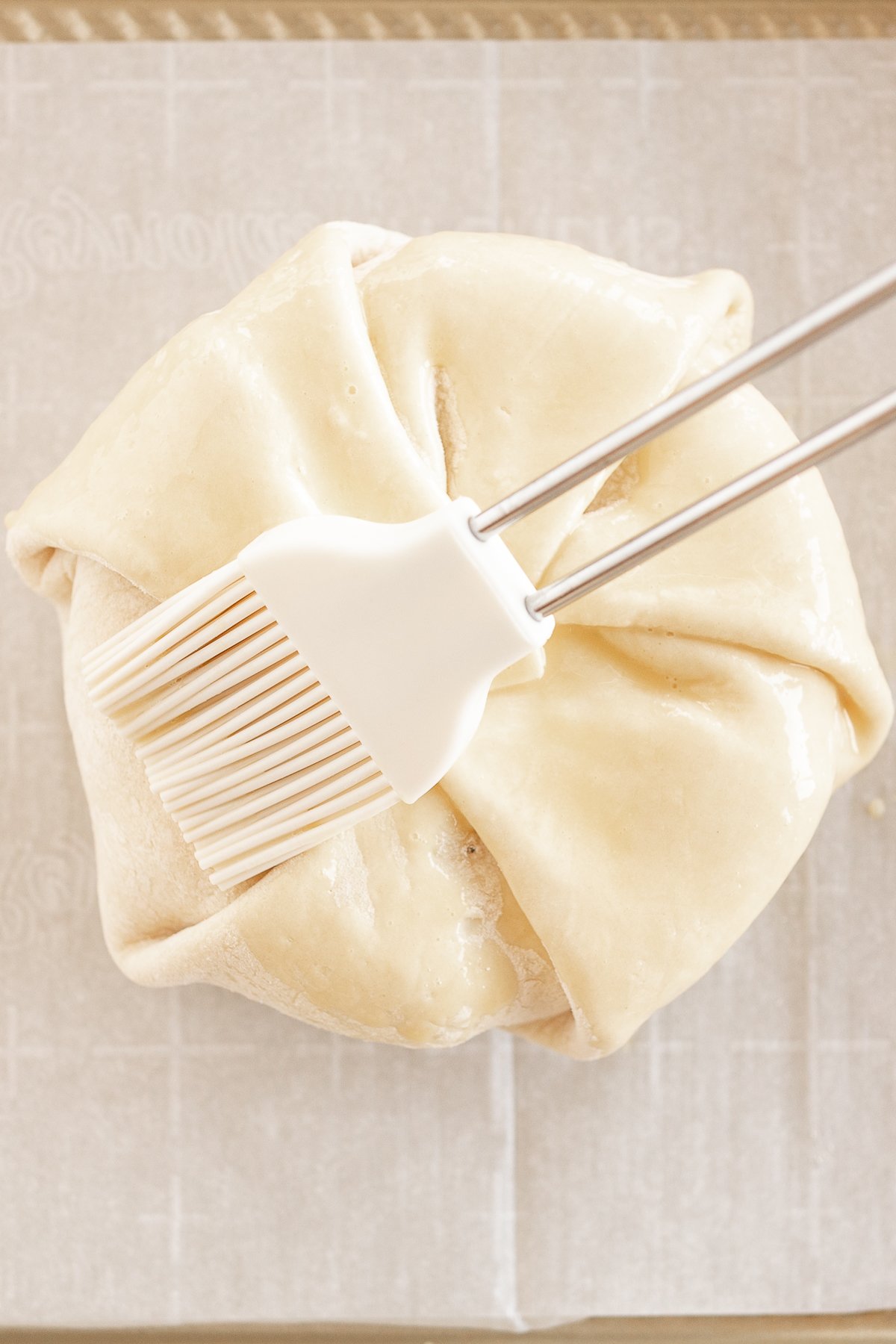 A pastry being sealed with kitchen gadgets, with a fork and a brush resting on top.