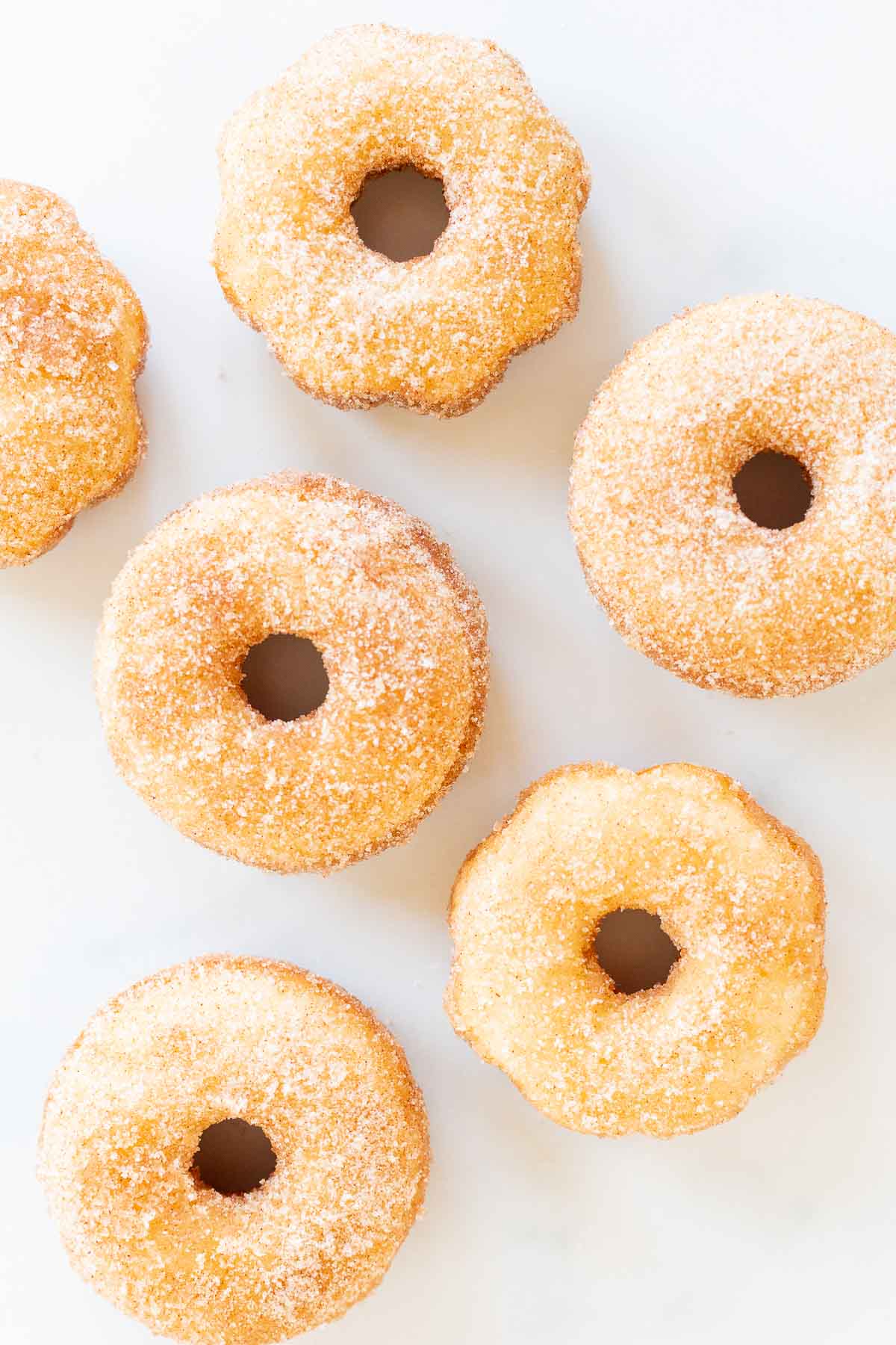 Five sugared donuts on a white surface for Mother's Day brunch.