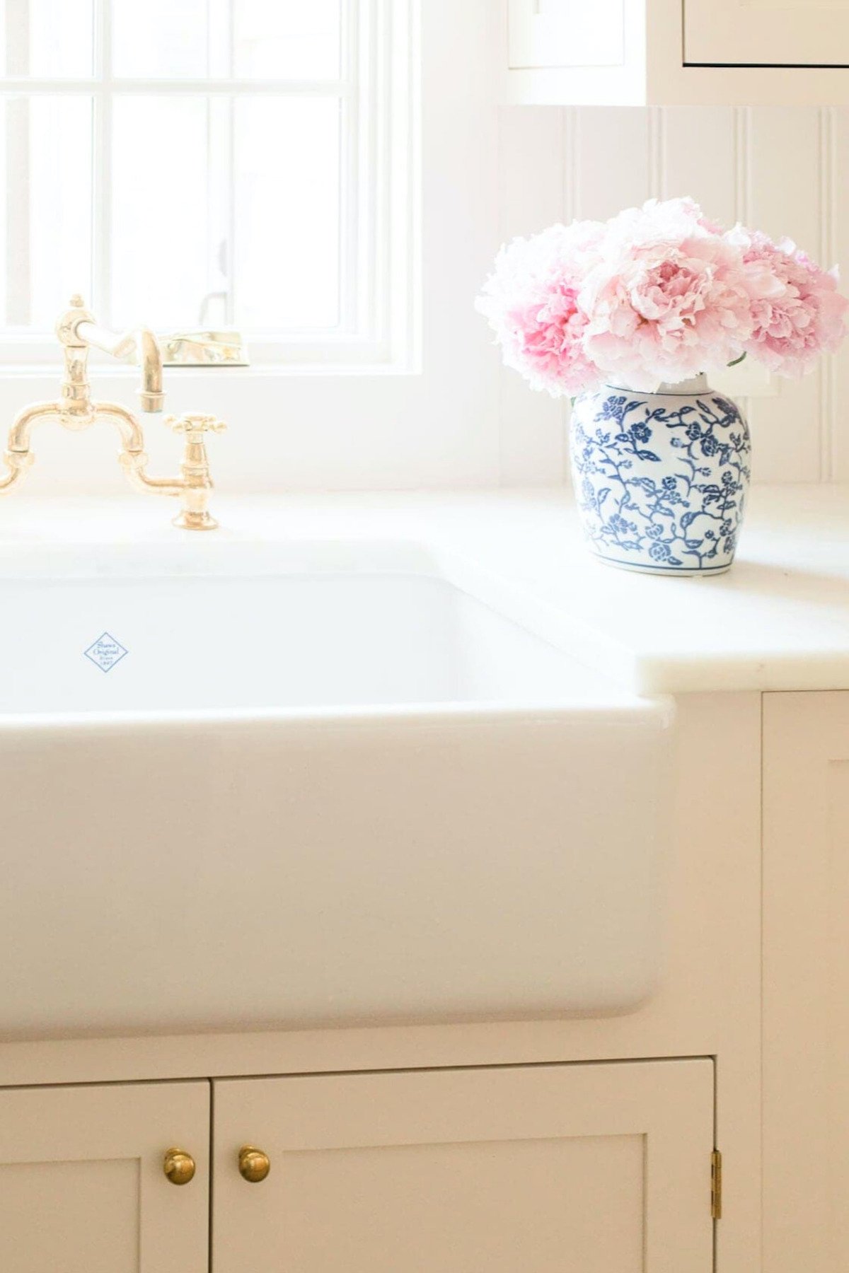 A vase of pink peony flowers on a counter top.