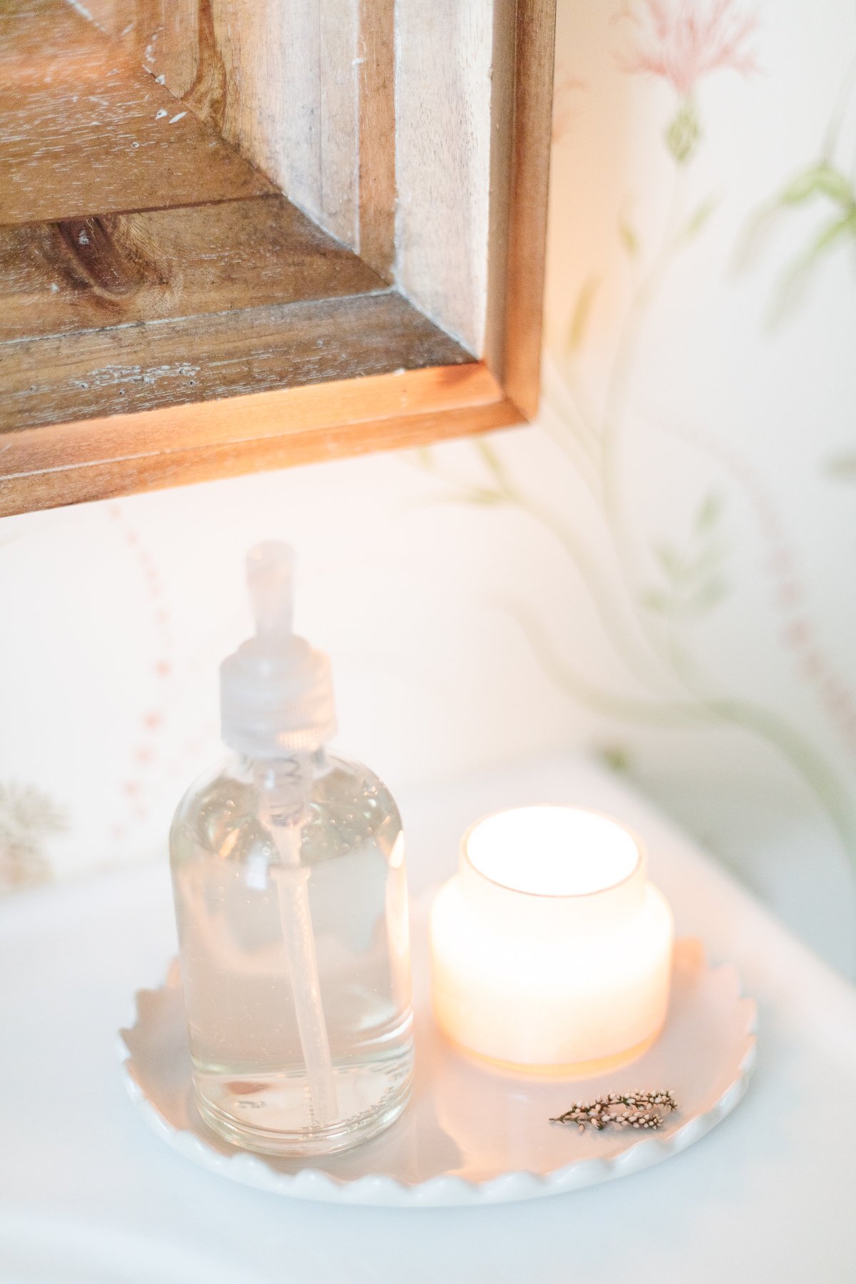 A scalloped candle sits on a plate next to a mirror.