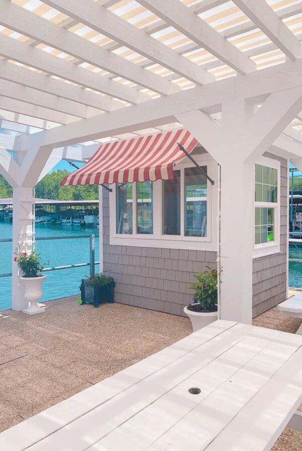 A dock restaurant on Table Rock lake with white picnic tables and a red and white striped awning.