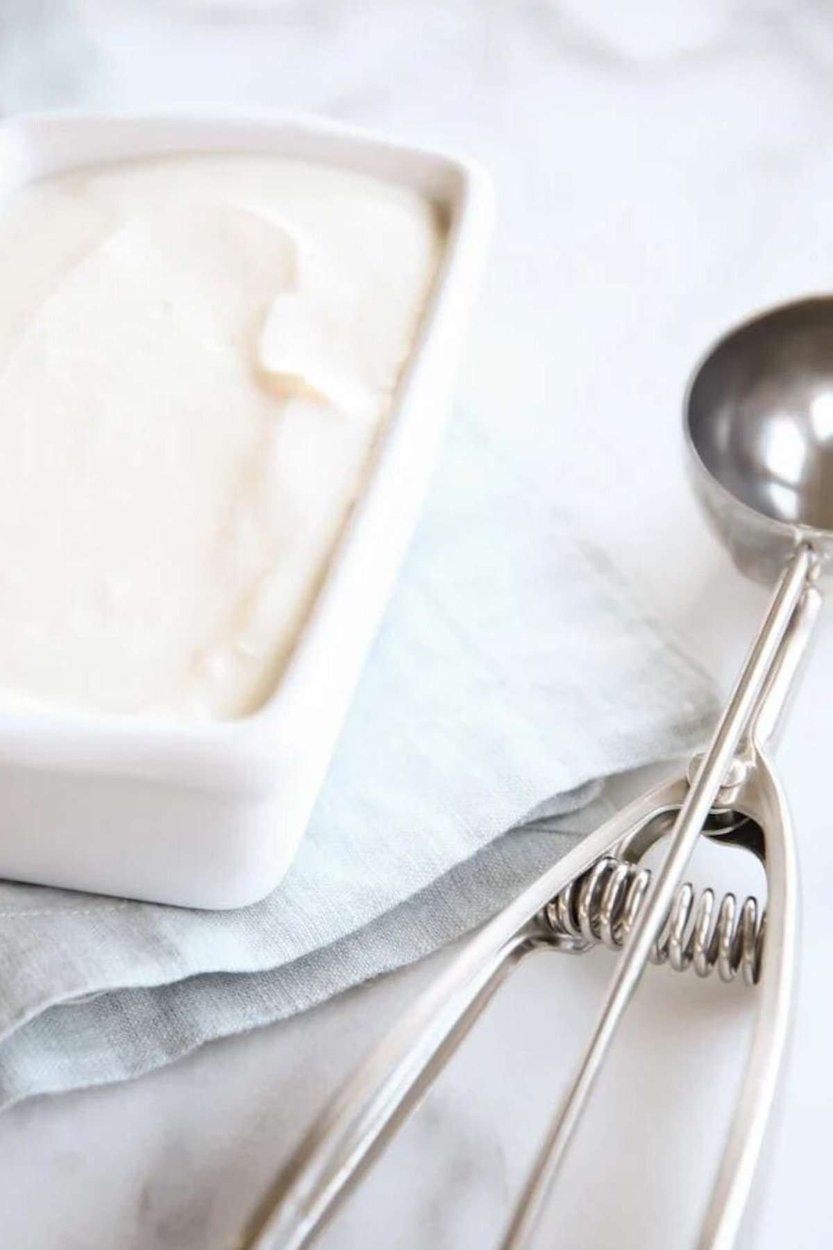 A bowl of homemade vanilla ice cream with a spoon next to it.