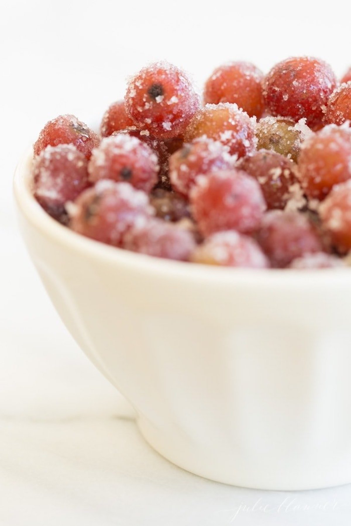 Christmas cranberries in a white bowl on a marble table.