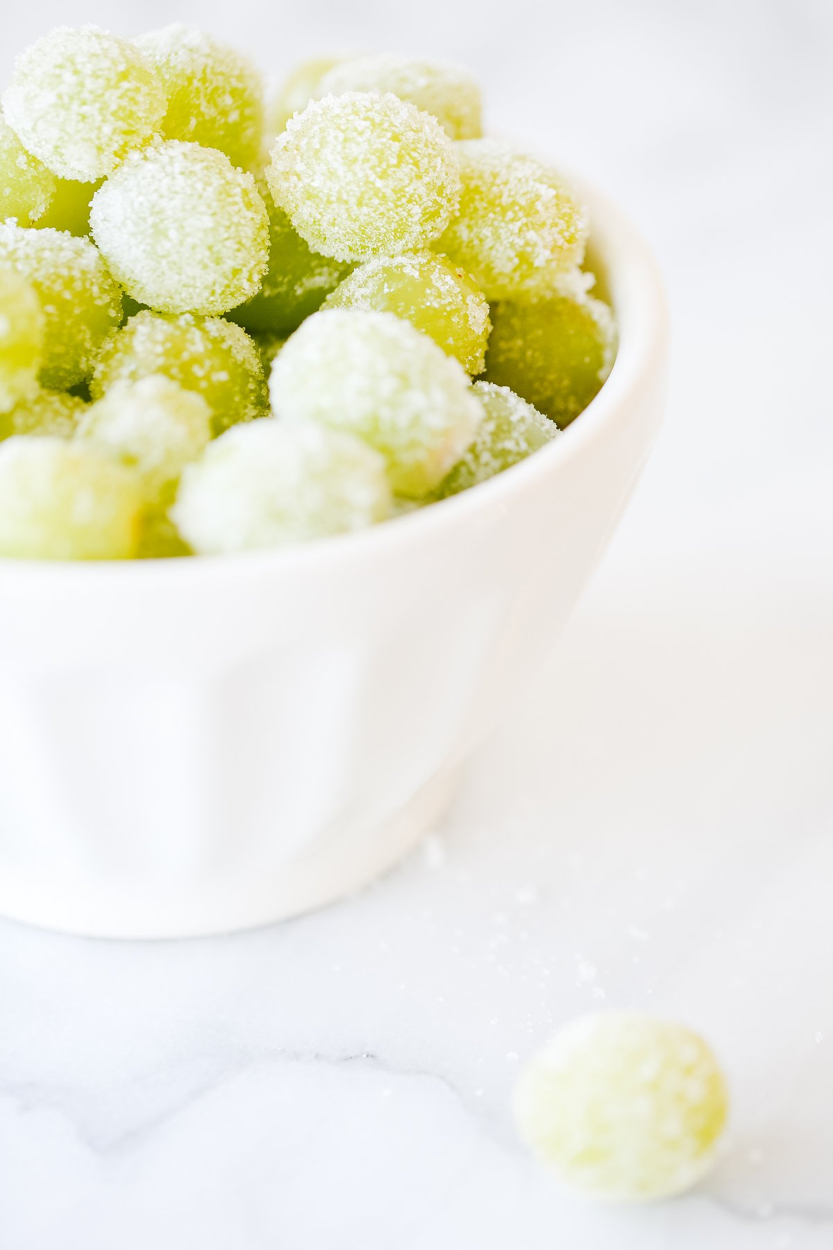 A bowl of Prosecco-coated grapes on a white surface.