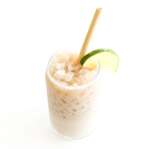 A close-up of an iced dirty Dr Pepper, garnished with a slice of lime on the rim, featuring a straw for sipping.