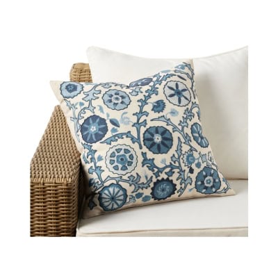 A beige cushion with blue floral patterns sits elegantly on a wicker sofa with an off-white cushion, offering a Pottery Barn look for less.