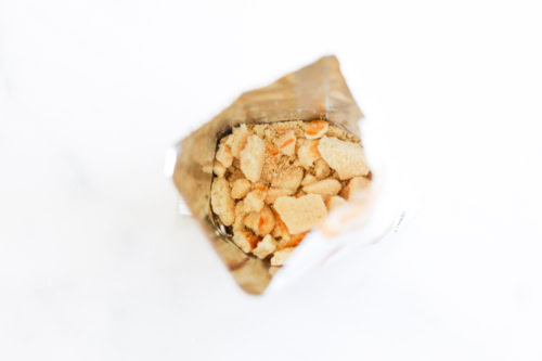 Open snack bag with crushed pieces on a white background.