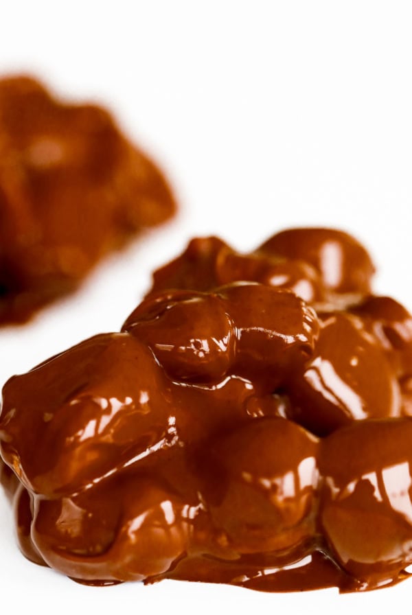 Close-up of clusters of chocolate-covered nuts on a white surface, reminiscent of classic Rocky Road Candy.