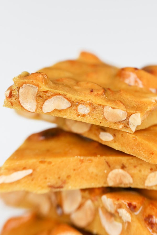 Close-up of peanut brittle pieces stacked on top of each other, showcasing the intricate texture and embedded peanuts.