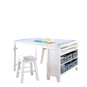 White drafting table with adjustable surface, integrated storage shelves, and multiple fabric bins—perfect for those seeking craft space ideas. Accompanied by a matching white stool.